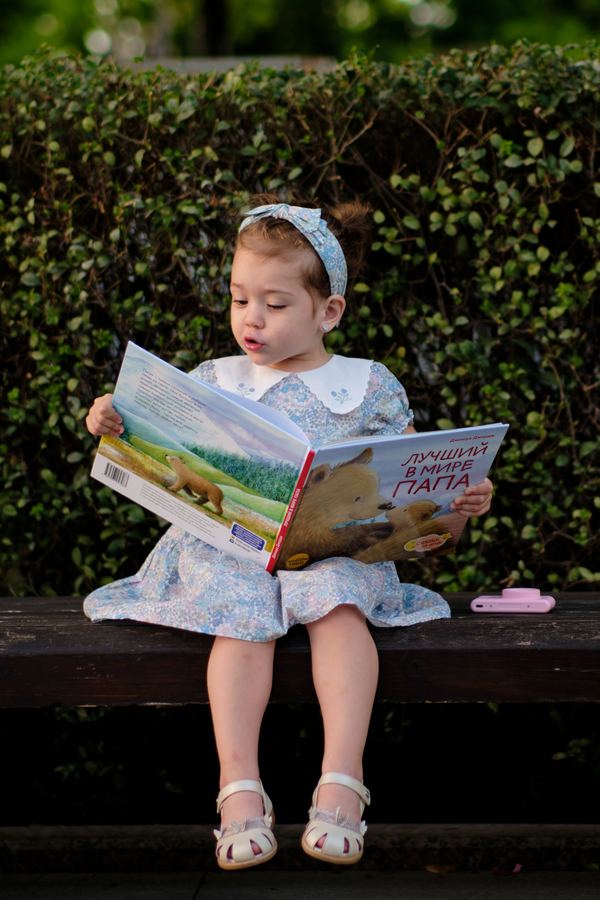 Девочка читает книгу на скамейке