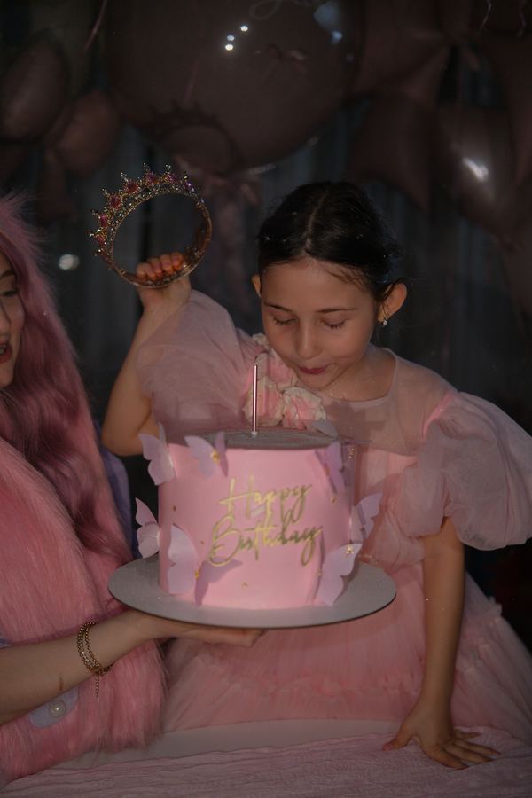 Именинница поднимает корону над тортом